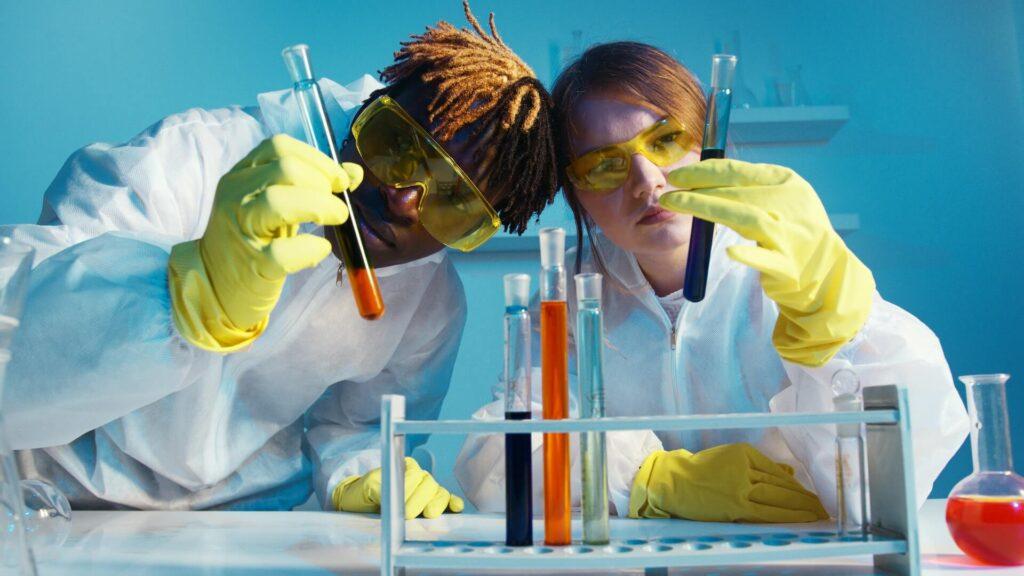 Male and female scientists analyzing chemicals in laboratory
