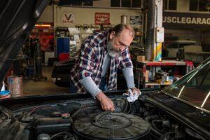 Man working on car engine inside professional auto garage